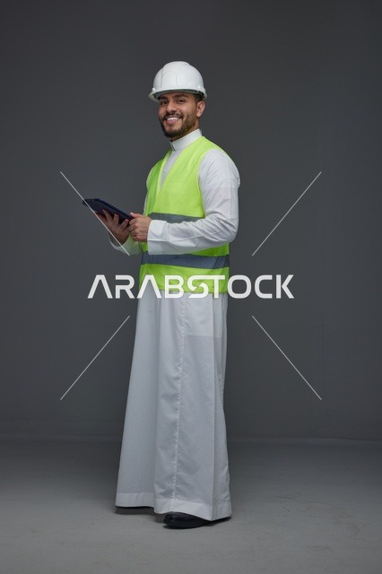 مهندس سعودي بمعدات السلامة يحمل جهازاً لوحياً