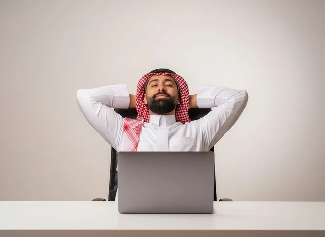 رجل سعودي بالزي التقليدي يستريح في مكتبه أمام المحمول