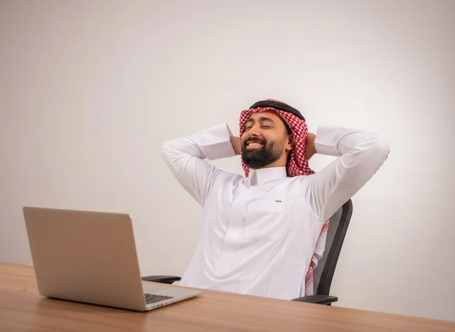 رجل أعمال سعودي مسترخي في المكتب مع كمبيوتر