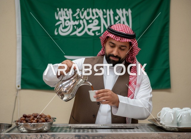 رجل سعودي يصب القهوة العربية أمام علم المملكة