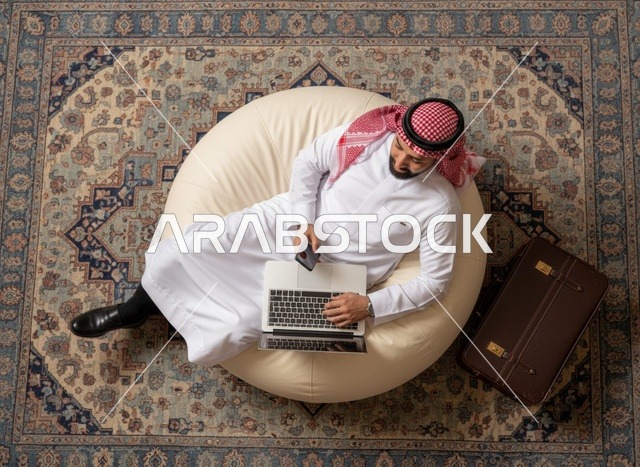 رجل سعودي يستخدم اللابتوب على كرسي بين باج