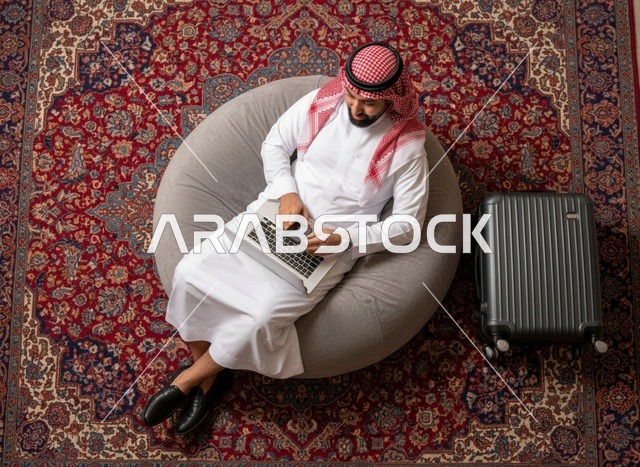 رجل سعودي مع حاسوب وحقيبة سفر لقطة علوية
