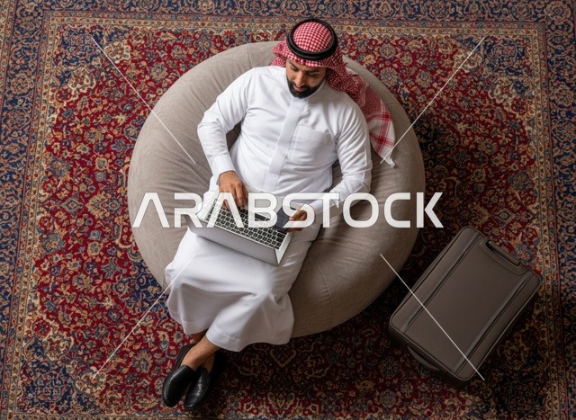 رجل سعودي يستخدم اللابتوب جالسًا على كرسي محشو