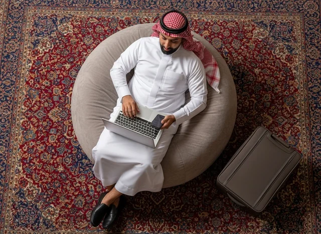 رجل سعودي يستخدم اللابتوب جالسًا على كرسي محشو