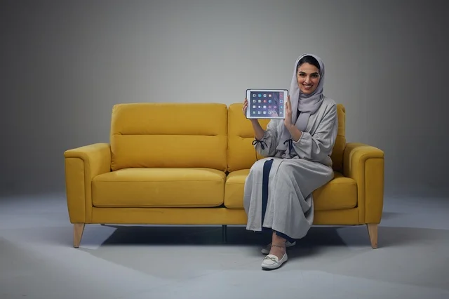 Saudi Woman on Yellow Sofa Holding Digital Tablet