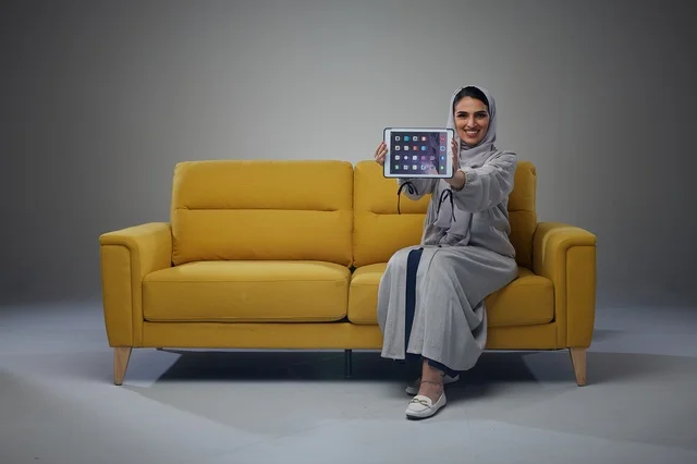Saudi Woman on Yellow Sofa Holding Digital Tablet