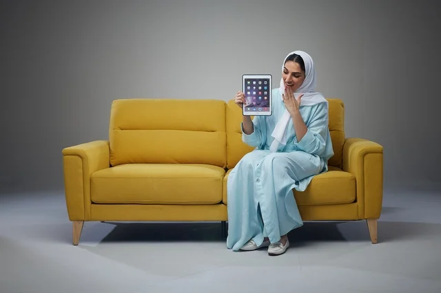 Saudi Woman Holding Digital Tablet on Yellow Sofa Studio