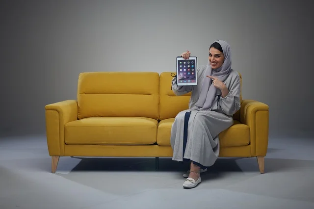 Saudi Woman with Tablet on Yellow Sofa Studio Shot