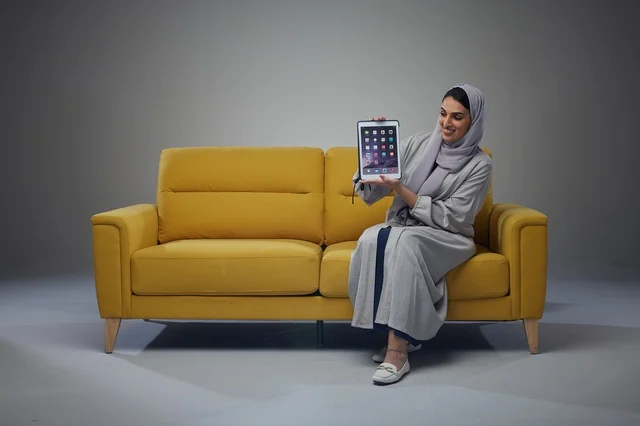 Saudi Woman on Yellow Sofa Holding Tablet in Studio