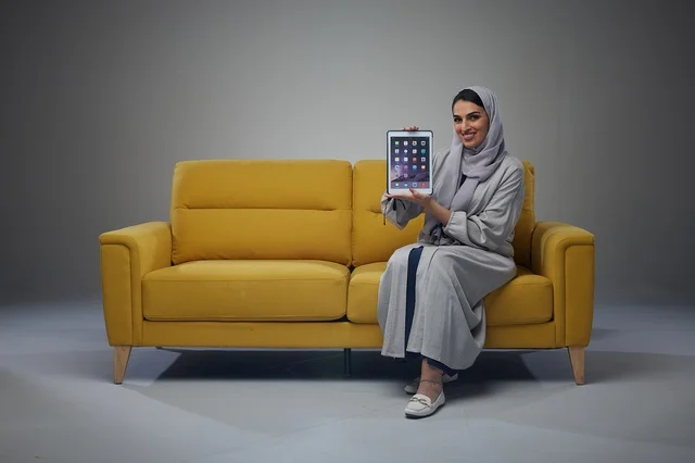 Saudi Woman on Yellow Sofa Holding Tablet in Studio