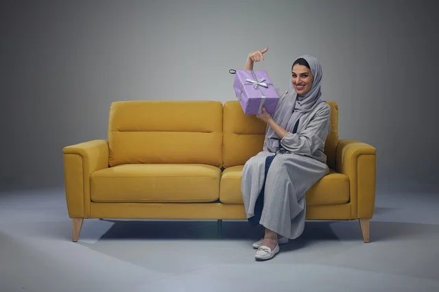 Saudi Woman with Gift Box on Yellow Sofa Saudi Woman with Gift Box on Yellow Sofa