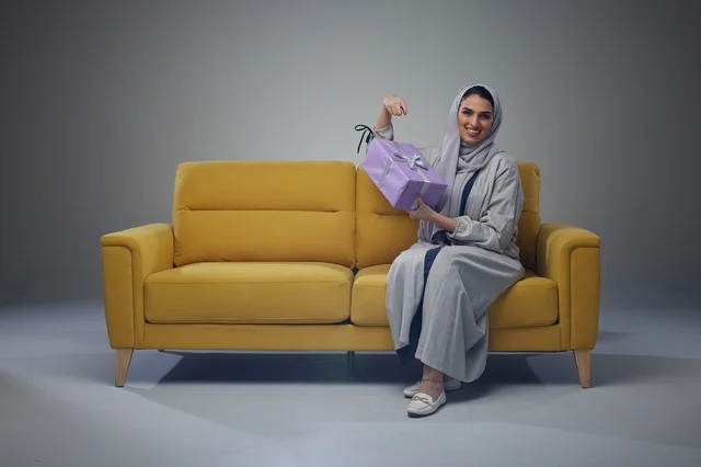 Saudi Woman on Yellow Sofa Holding Gift Box Saudi Woman on Yellow Sofa Holding Gift Box