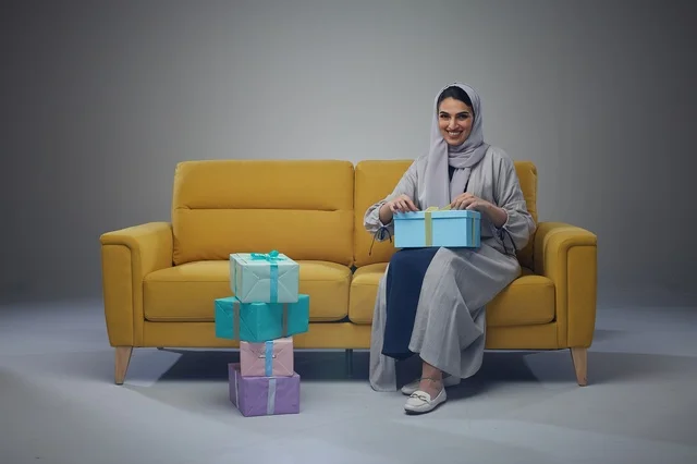 Saudi Woman on Yellow Sofa with Gift Boxes