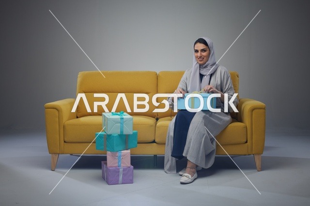 Saudi Woman on Yellow Sofa with Gift Boxes - Photo