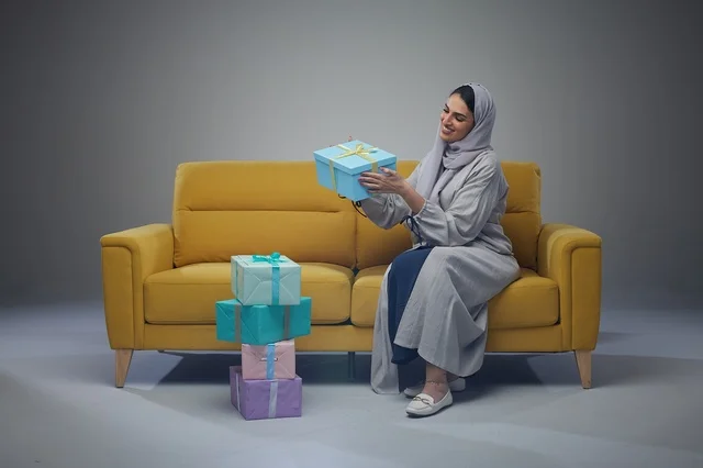 Saudi Woman with Gift Boxes on Yellow Sofa