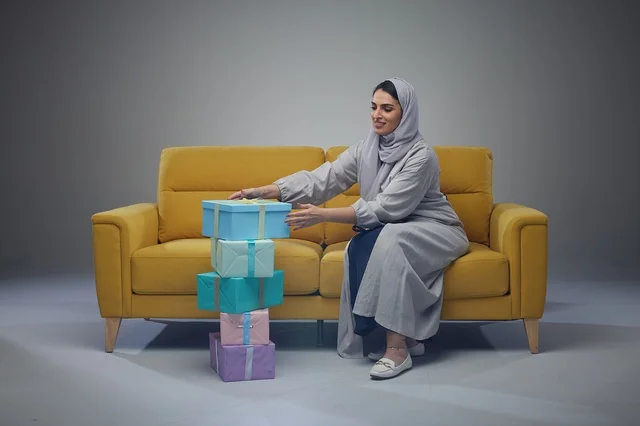 Saudi Woman on Yellow Sofa with Colorful Gift Boxes