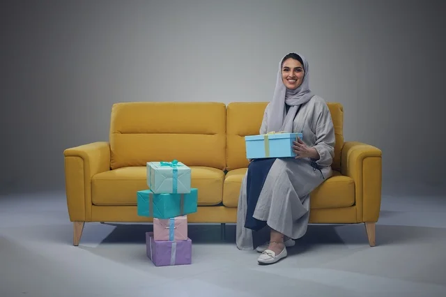 Saudi Woman with Gift Boxes on Yellow Sofa