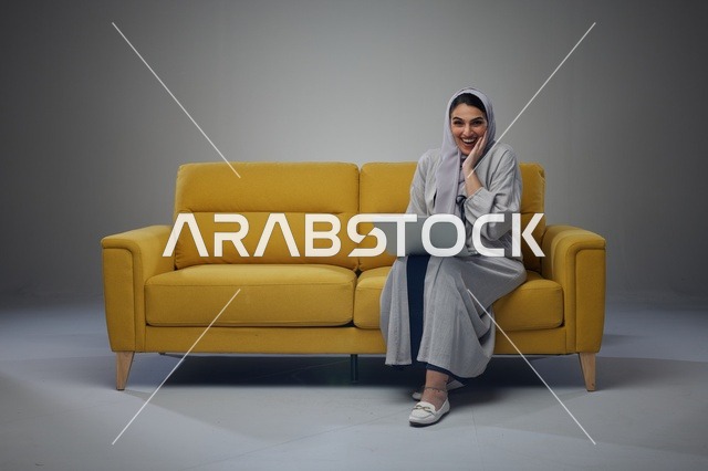 امرأة سعودية تستخدم الكمبيوتر المحمول على أريكة صفراء