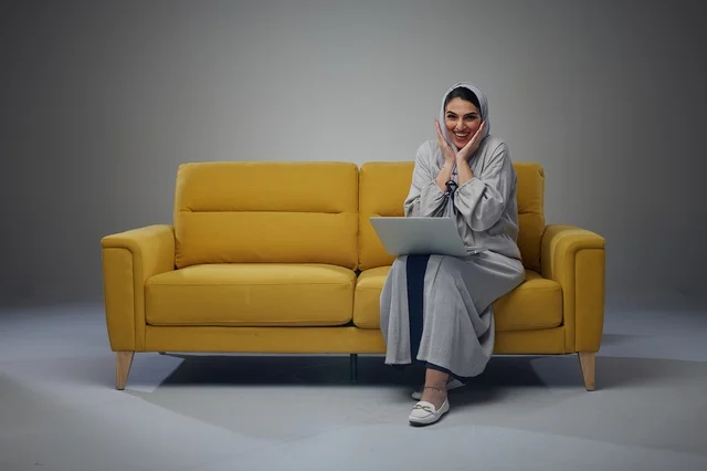 Saudi Woman Sitting on Sofa Using Laptop and interacting with the camera