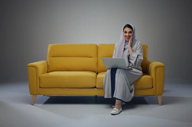 Saudi Woman with Laptop on Yellow Sofa