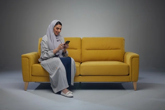 Saudi Woman Using Smartphone on Yellow Sofa