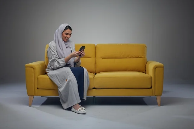 Saudi Woman on Yellow Sofa Using Smartphone