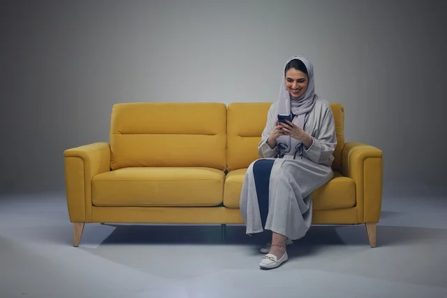 Saudi Woman Sitting on Sofa and using smartphone