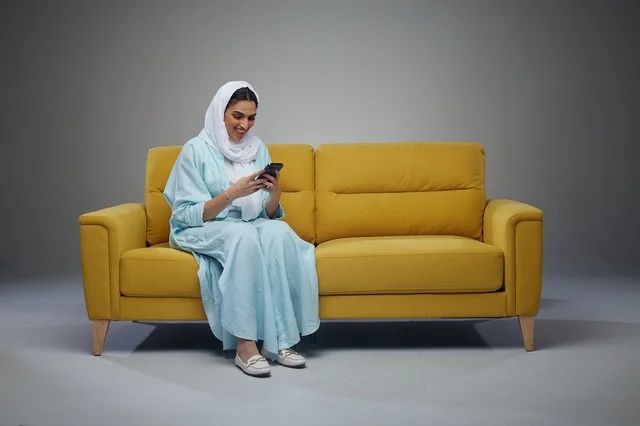 Saudi Woman on Yellow Sofa Using Smartphone