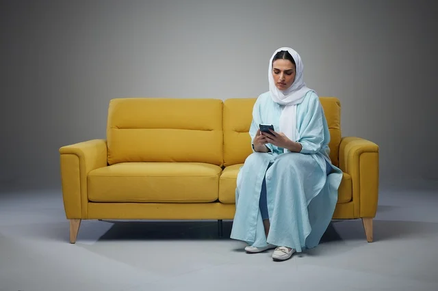 امرأة سعودية تستخدم الهاتف الذكي على أريكة