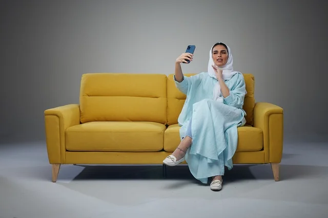Saudi Woman Taking Selfie on Yellow Sofa in Studio