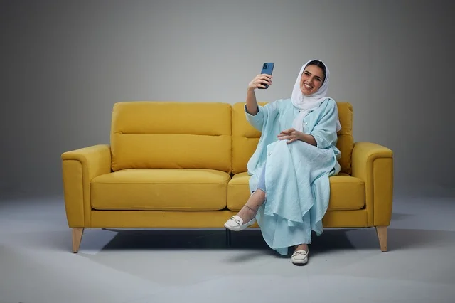 Saudi Woman Taking Selfie on Yellow Sofa Studio