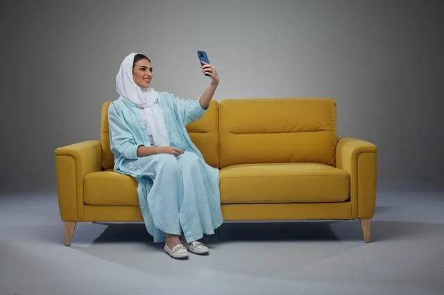 امرأة سعودية تلتقط صورة سيلفي على أريكة صفراء
