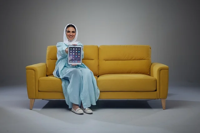 Saudi Woman on Yellow Sofa Holding Digital Tablet