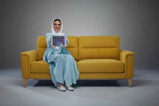 Saudi Woman Holding Digital Tablet on Yellow Sofa Studio