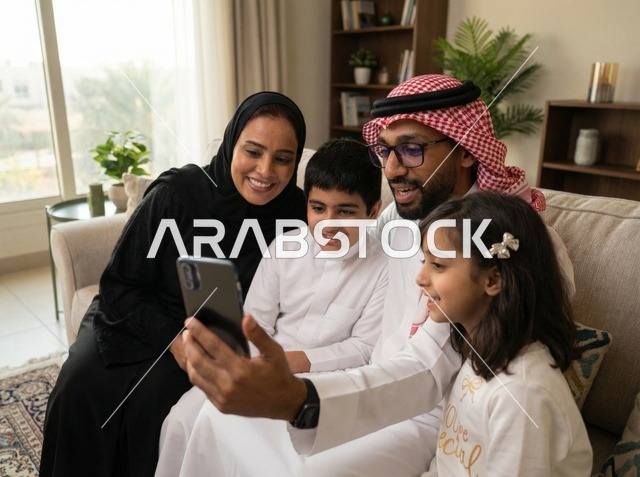 عائلة سعودية تستخدم الهاتف الذكي في غرفة المعيشة بالمنزل