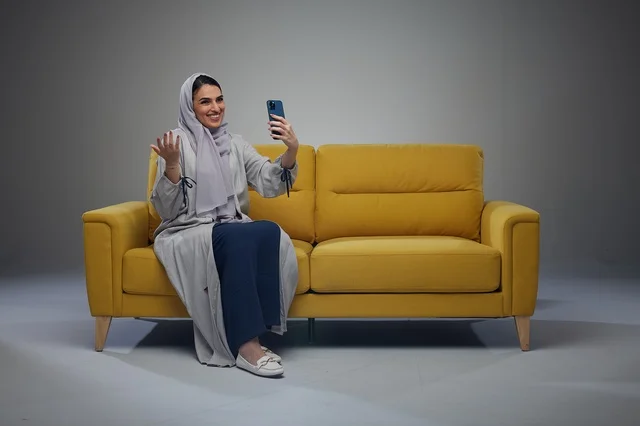 Saudi Woman Taking Selfie on Yellow Sofa in Studio