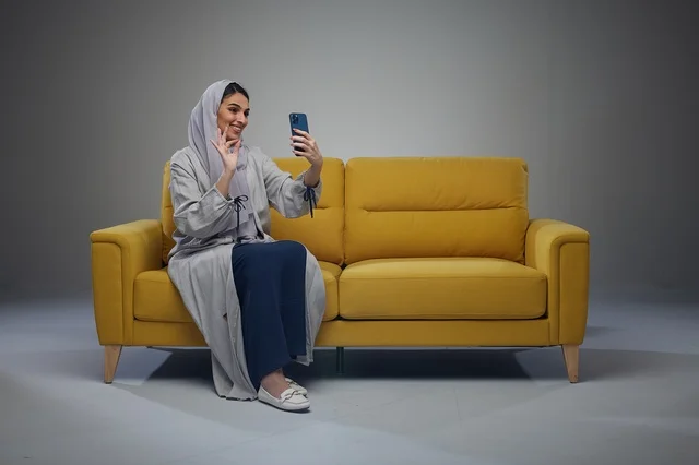 امرأة سعودية على أريكة صفراء تلتقط صورة سيلفي
