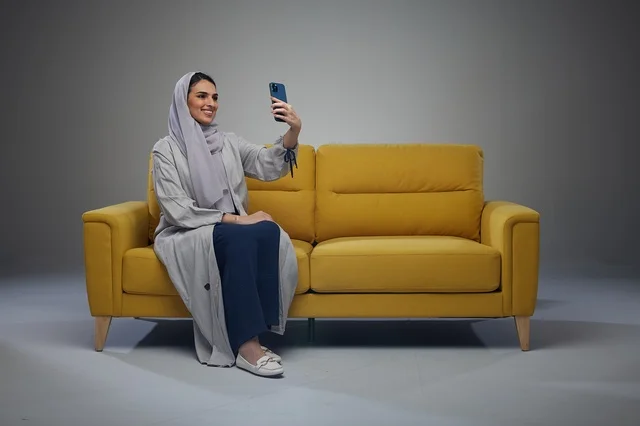 Saudi Woman Taking Selfie on Yellow Sofa in Studio