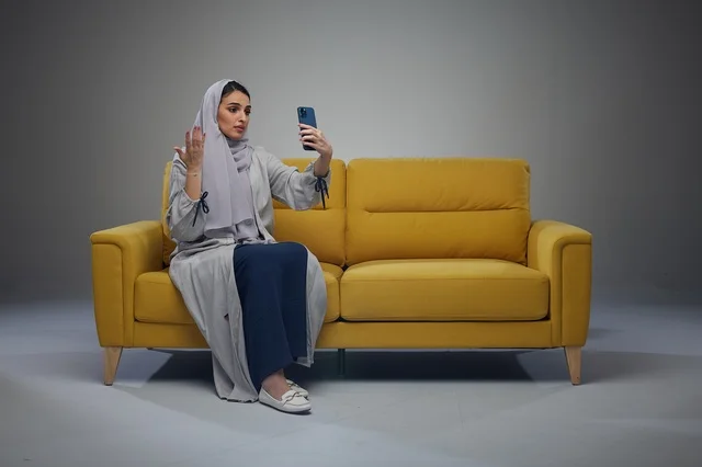 امرأة سعودية تلتقط سيلفي على أريكة صفراء في استوديو
