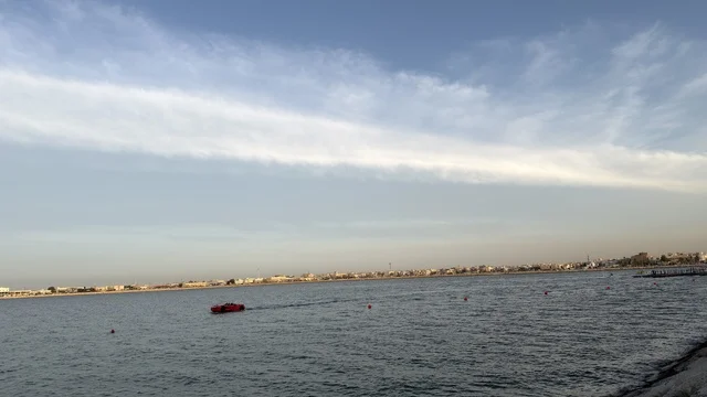 Red Boat at Qatif Seafront with Urban Skyline