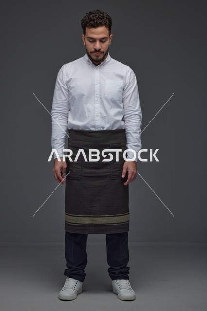 رجل سعودي بمئزر أسود يقف في الاستوديو
