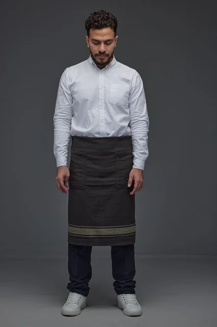 رجل سعودي بمئزر أسود يقف في الاستوديو