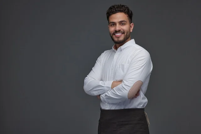 رجل سعودي مبتسم بقميص أبيض ومئزر أسود