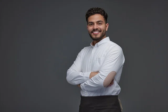 Smiling Saudi Man in Black Apron Professional Portrait