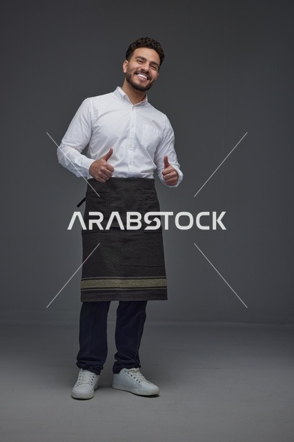 رجل سعودي بمئزر يبتسم ويشير بعلامة الإعجاب في الاستوديو