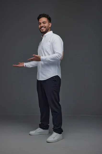 Saudi Man Pointing and Smiling on Grey Background