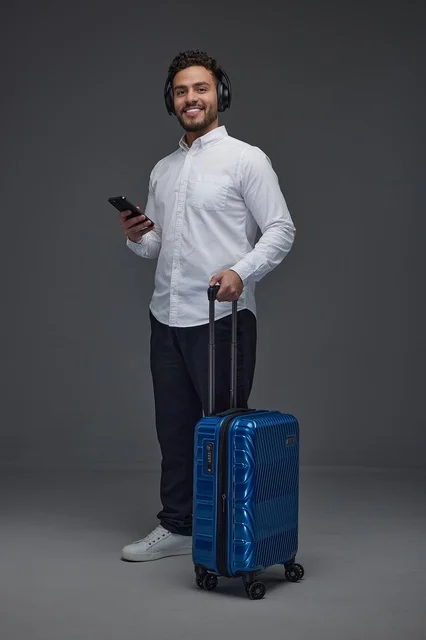 Saudi Traveler with Blue Suitcase and Headphones