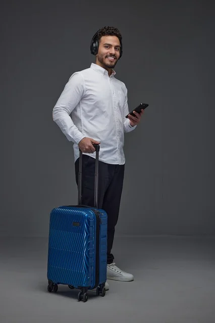 Saudi Traveler with Blue Suitcase and Over-Ear Headphones