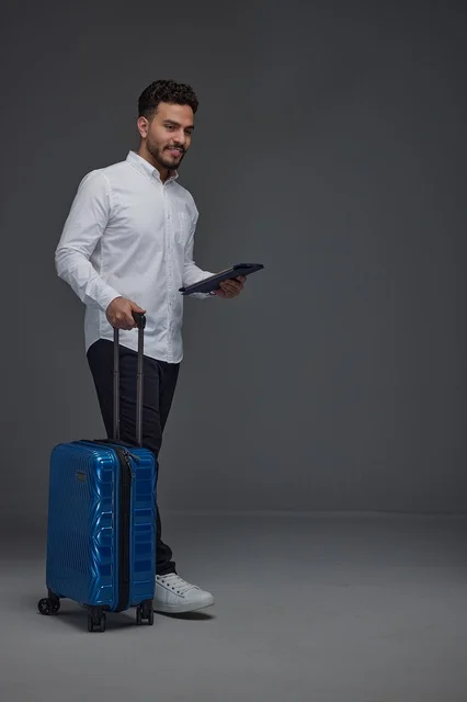 Saudi Traveler with Blue Suitcase and Digital Tablet