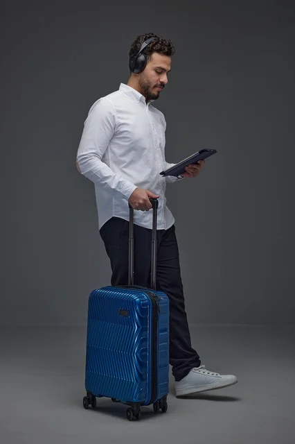 Saudi Traveler Using Tablet with Luggage and Headphones